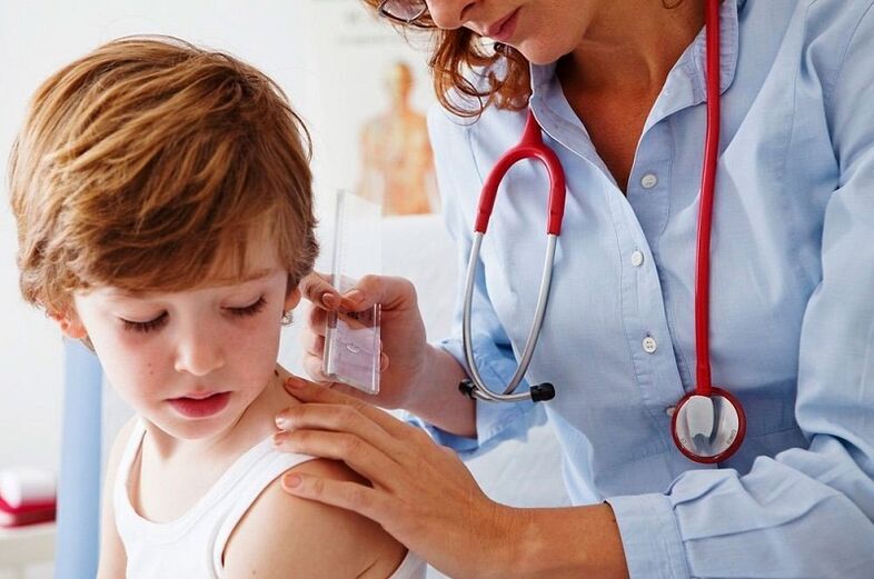 The doctor examines a child with papilloma on the body